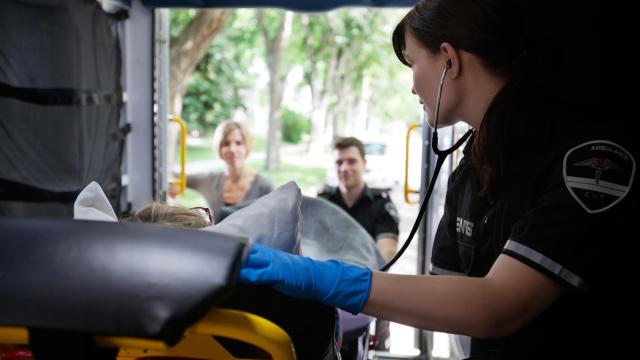 An EMT sits inside an ambulance with a patient.