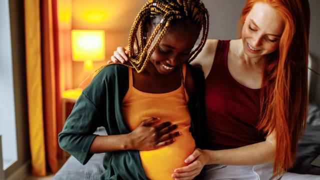 Two adults with their hands on one's pregnant belly
