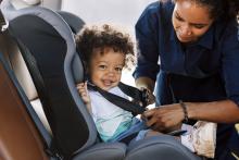Parent securing their child in a safety seat in a car