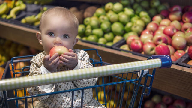 Baby eating an apple in a shopping cart