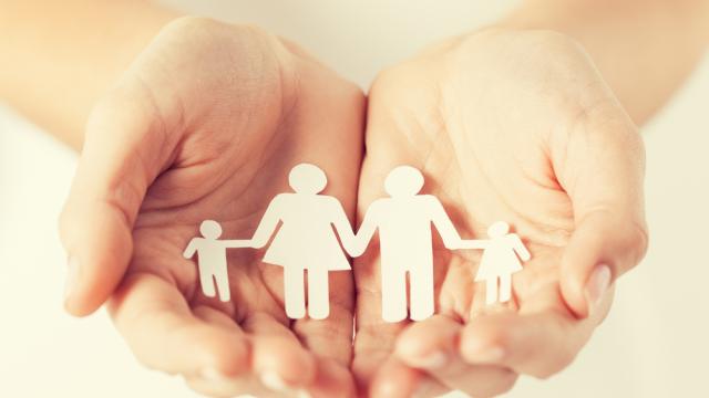 hands holding a cutout of family with two kids