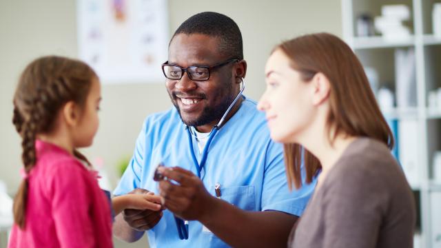 Doctor examining a child while adult watches