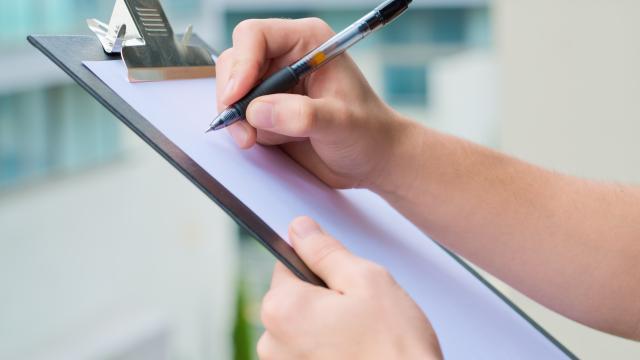 Hands holding a clipboard with a pen