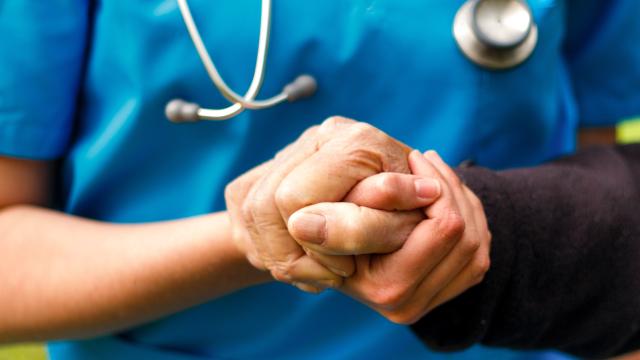 Healthcare provider's hand holding a patient's hand