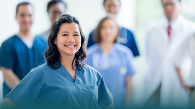 health professional wearing scrubs smiles with people in background