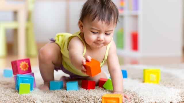 A toddler playing with blocks on an area rug at home