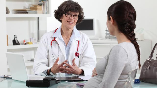 A pregnant adult talks with her doctor at a clinic