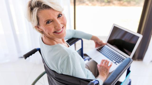 An adult in a wheelchair with an open laptop on her knees