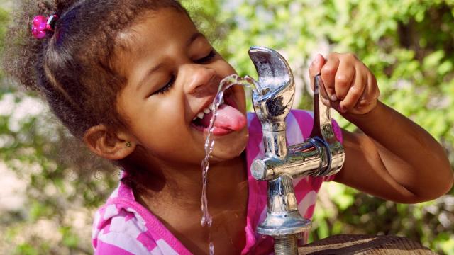 A child drinking from a bubbler outside