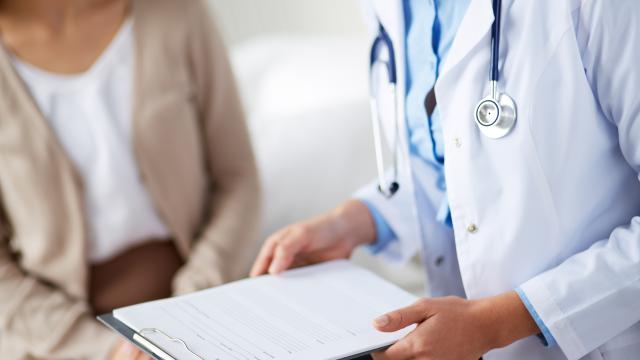 Doctor holding clipboard with papers discussing medical form with patient