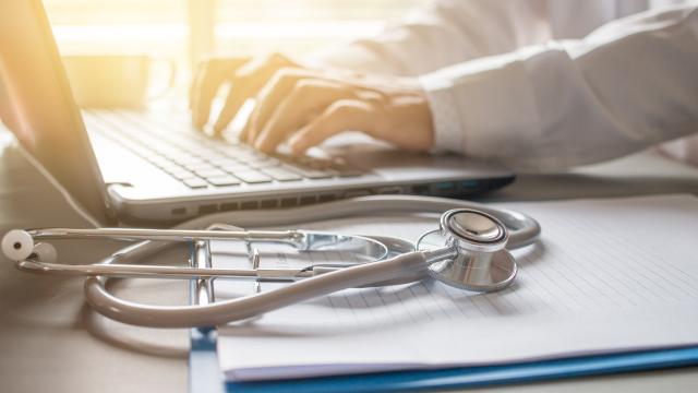 Doctor working on computer with stethoscope on desk