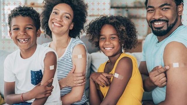 Two adults, two children showing vaccinated arms with Band-Aids