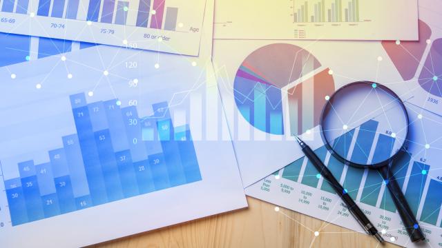 Various graphs, magnifying glass and pen on table showing data analytics