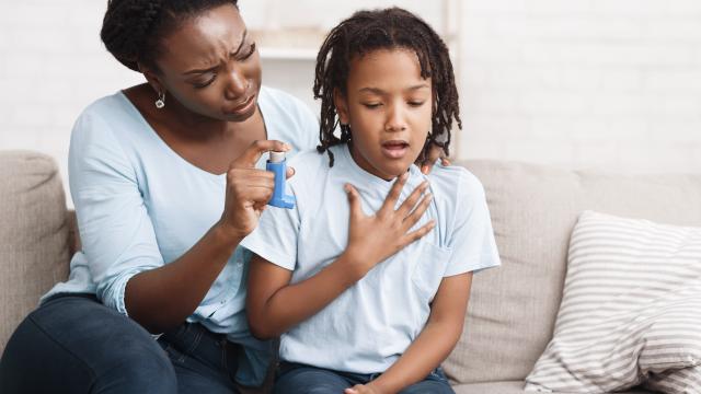 Adult holding an inhaler for child having an asthma attack