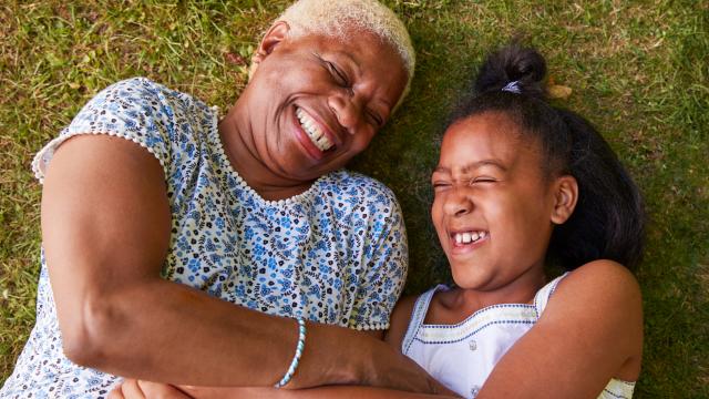 Senior and teen lying on the grass laughing together