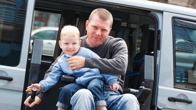 An adult and a child getting out of a van using a wheelchair lift
