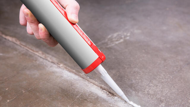 Person using a tube of sealant to seal cracks