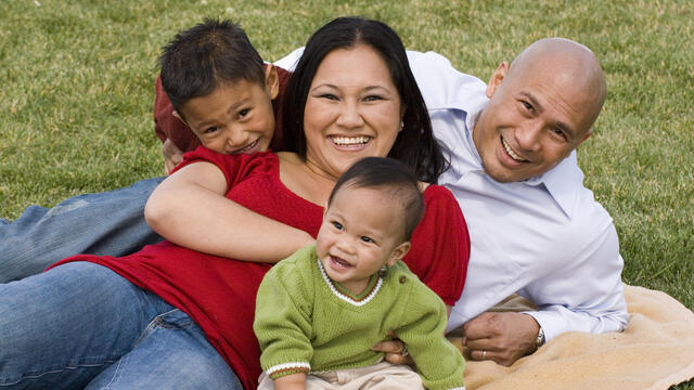 Two adults and two kids on a blanket at the park