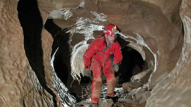 Adult spelunking. Bending over while going through cave passage