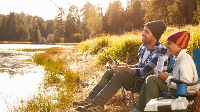 Adult and child sitting on a bank fishing