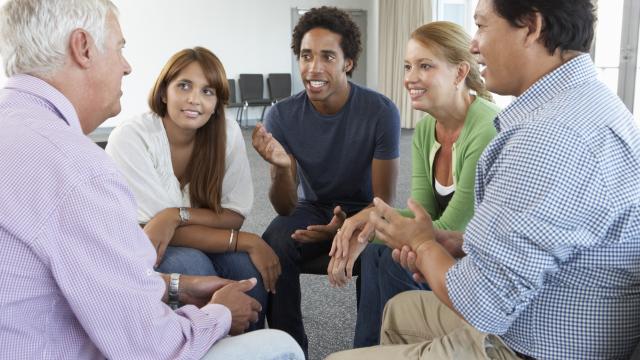 Five adults sitting in a tight circle talking.