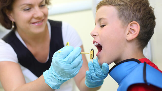 A dental hygienist putting a bite-blocker in a child's mouth.