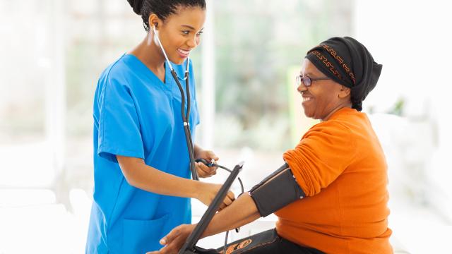 A smiling nurse check a patient's blood pressure.