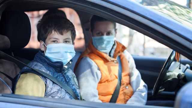 Two people wearing medical masks while sitting in a car
