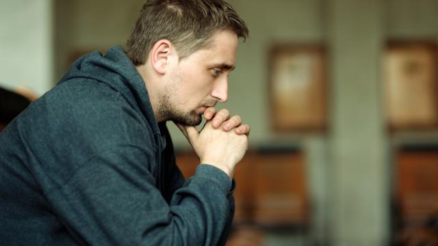 A person thinking serious thoughts with chin on folded hands