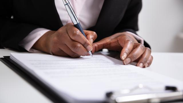 Hand signing papers in a clipboard