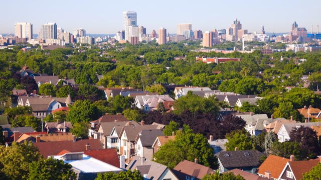 Looking over the neighborhood homes with trees and downtown buildings in the background, Milwaukee