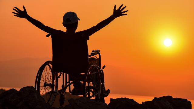 Silhouette of an adult in a wheelchair at sunset
