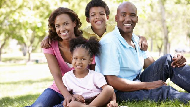 Two adults and two children on grass in a park