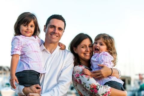 Two adults each holding a child on a white background