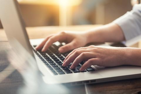 Hands typing on a laptop