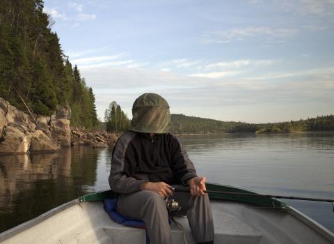 An adult with mosquito netting fishing