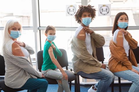 Four people showing their arm with band-aid after vaccination