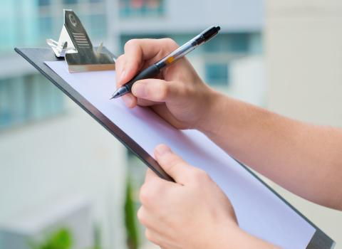 Close up of hands holding a clipboard with a pen