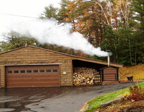 Garage with an outside wood burner and stack of logs