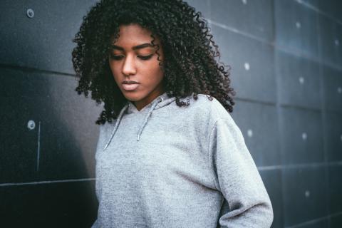 Reflective teen standing next to a wall