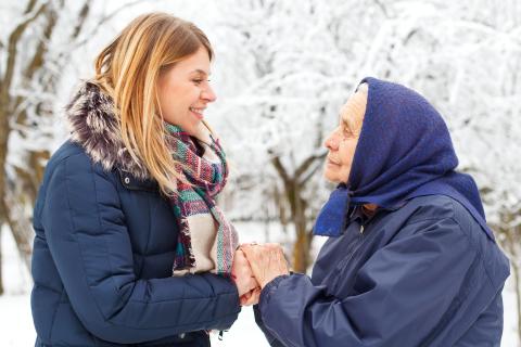 Older adult holding hands of young adult outside in winter