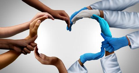 Multiple hands forming a heart with back to back head shapes in the middle