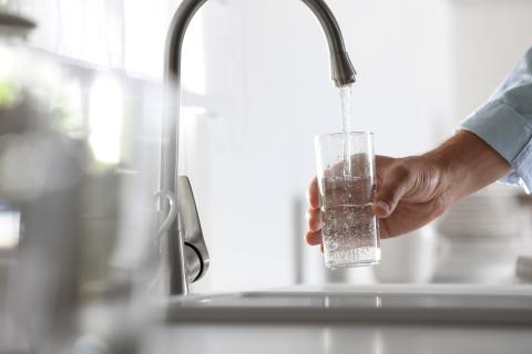 Glass of water being filled at a faucet