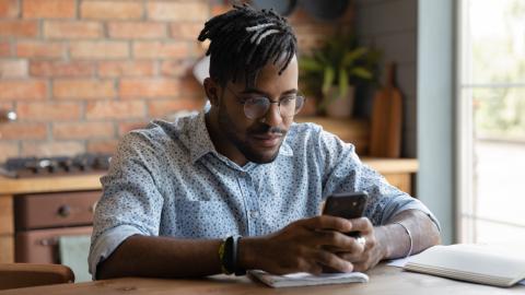 Person sitting at a table scrolling through their phone