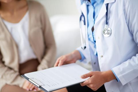 Doctor holding clipboard with papers discussing medical form with patient