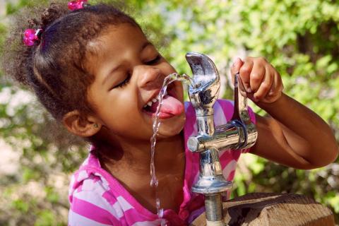 A child drinking from a bubbler outside