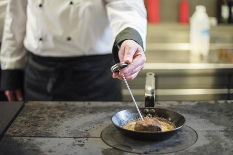 Chef checking temperature of meat using a meat thermometer