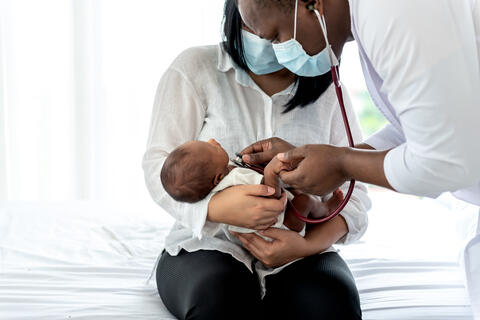 Doctor checking a newborn baby being held by their mother