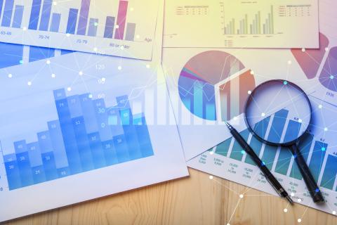 Various graphs, magnifying glass and pen on table showing data analytics