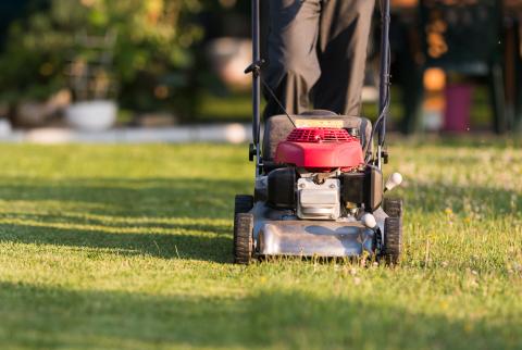 Lawnmower being used to cut grass by a person outside